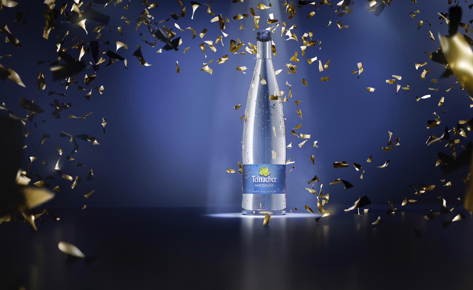 Teinacher Genussflasche blauer Hintergrund mit Goldkonfetti